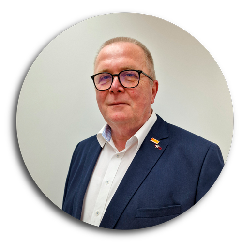 Ein Portraitbild des Gesch&auml;ftsf&uuml;hrers, in blauem Sakko, mit kurzen grauen Haaren und Brille.